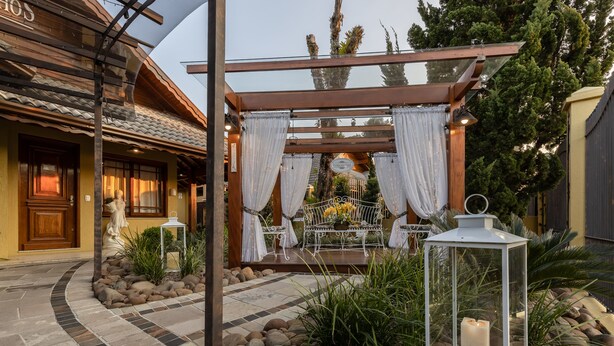 Un patio con una pérgola, mobiliario exterior y un farol.