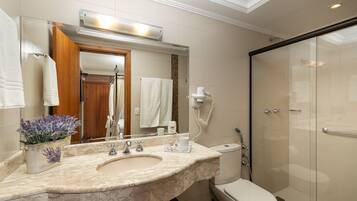 A modern bathroom with a marble sink, a toilet, a glass shower enclosure, and a mirror with a towel rack.