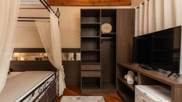 A bedroom with a bed, a TV, a wardrobe, and a small white appliance.