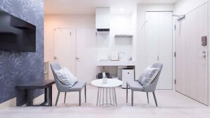 A modern room with a round table and two chairs, a TV mounted on the wall, and a wardrobe. - Guestvilla Hakone Miyanoshita (Hakone)