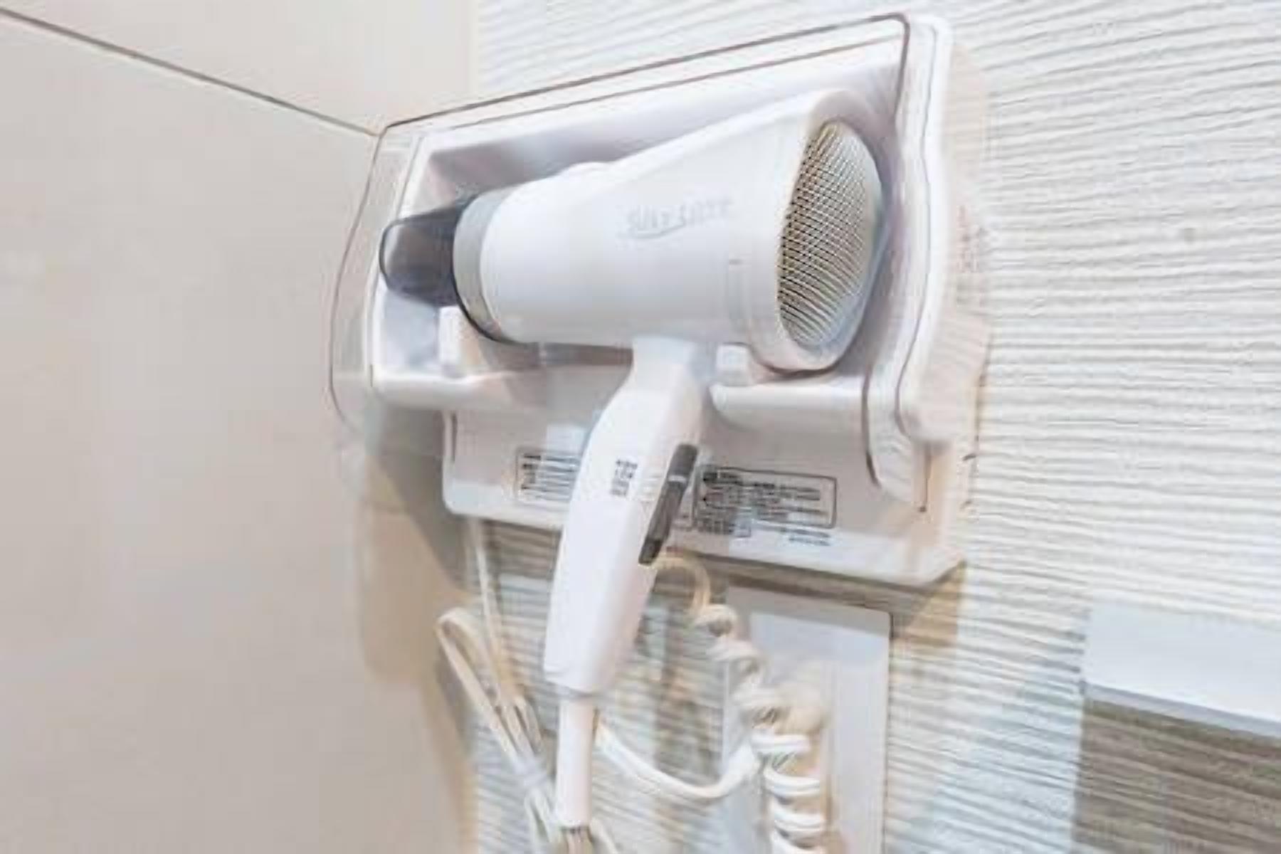 A hair dryer mounted on a wall with a cord.