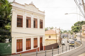 Vista da rua com um edifício de fachada clássica, uma estrada estreita e um elétrico.