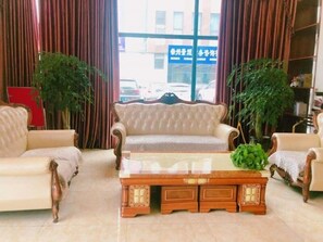 Um quarto com sofá, mesa de centro de madeira e duas plantas em vasos.