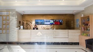 A hotel reception area with a modern design, featuring a wooden reception desk, a digital display, and a marble floor.