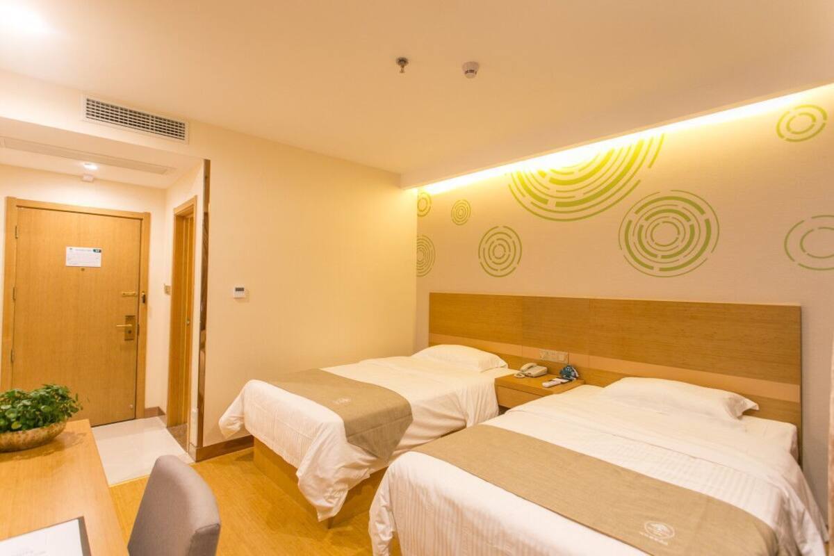 Ein Hotelzimmer mit zwei Betten, einem hölzernen Kopfteil, einem Nachttisch mit Telefon und einer Wand mit kreisförmigen Mustern.