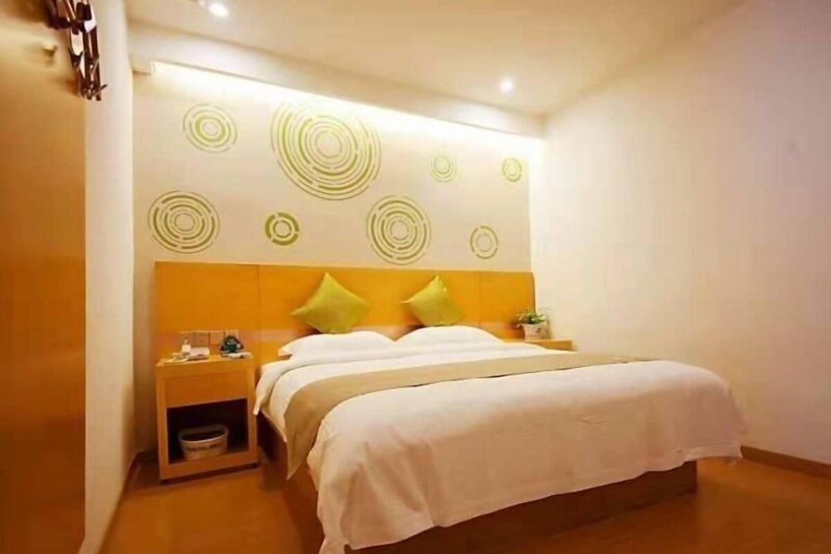 Ein Hotelzimmer mit Bett, Nachttisch und Wand mit kreisenden Mustern.