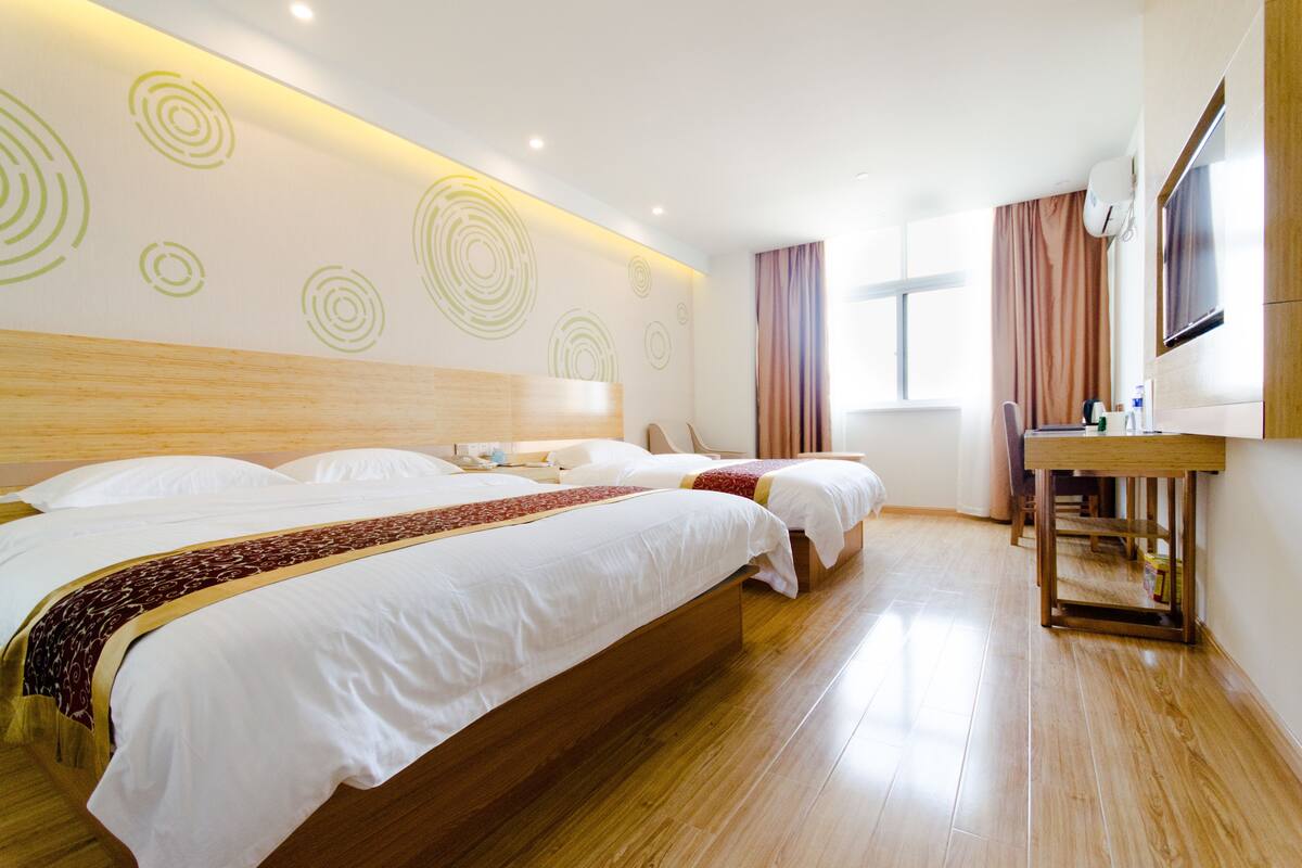 Ein Hotelzimmer mit zwei Betten, einem Holzkopfstück, einem Schreibtisch und einem Fernseher.