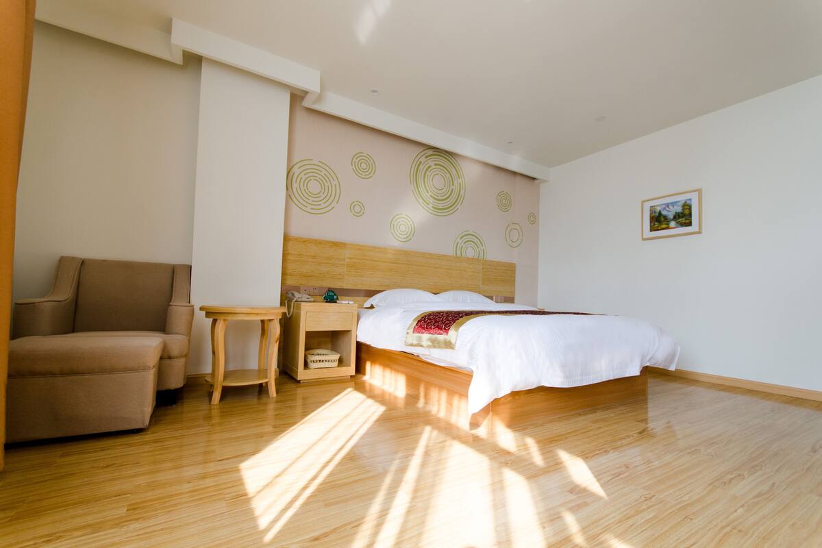 Ein Hotelzimmer mit Bett, Stuhl, Nachttisch und einer Wand mit kreisenden Mustern.
