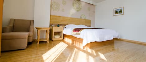 A hotel room with a bed, a chair, a bedside table, and a wall with circular patterns.
