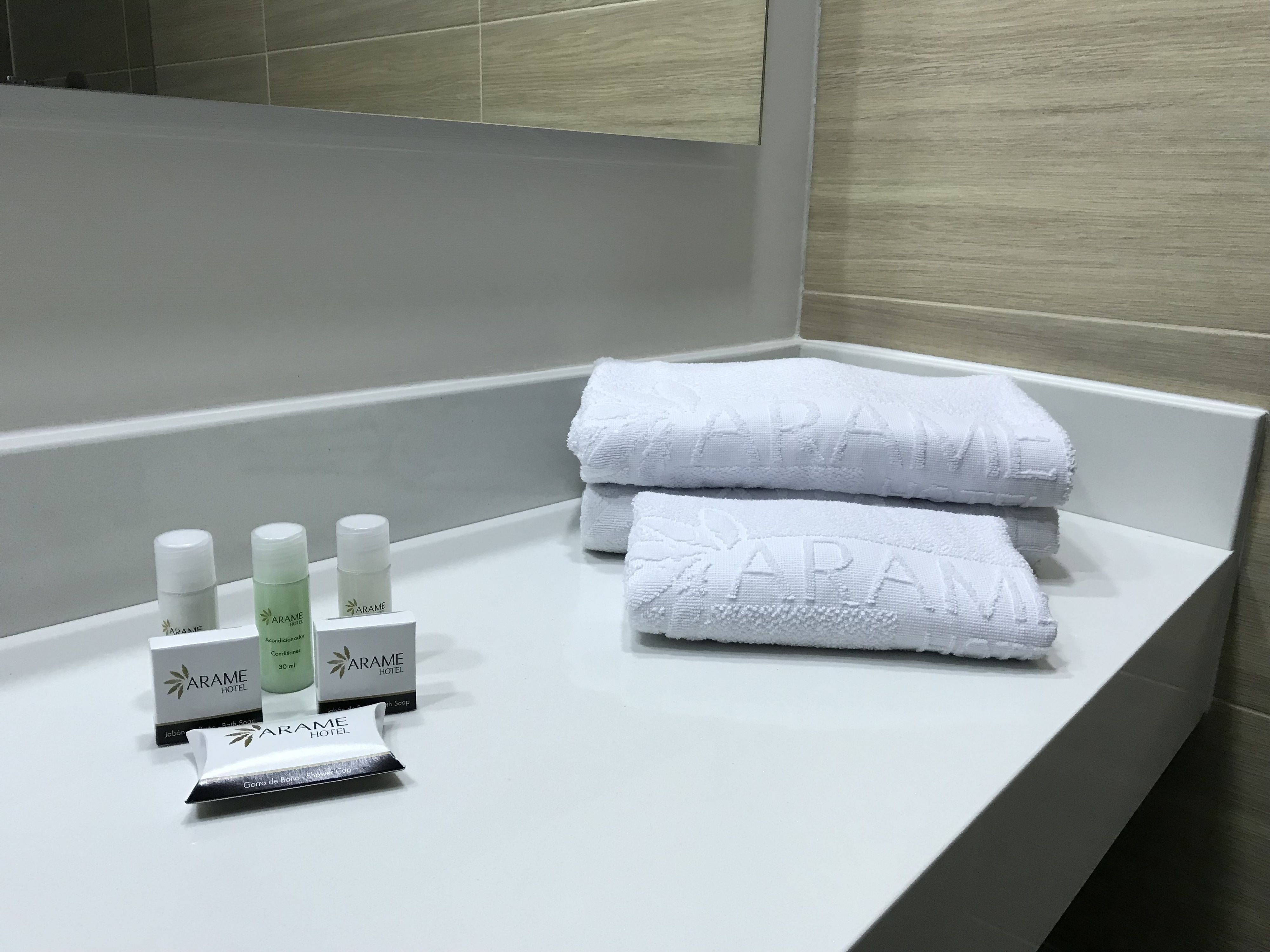 Un baño con una bañera blanca, dos toallas blancas y artículos de aseo, incluyendo una pastilla de jabón y un tubo de loción.
