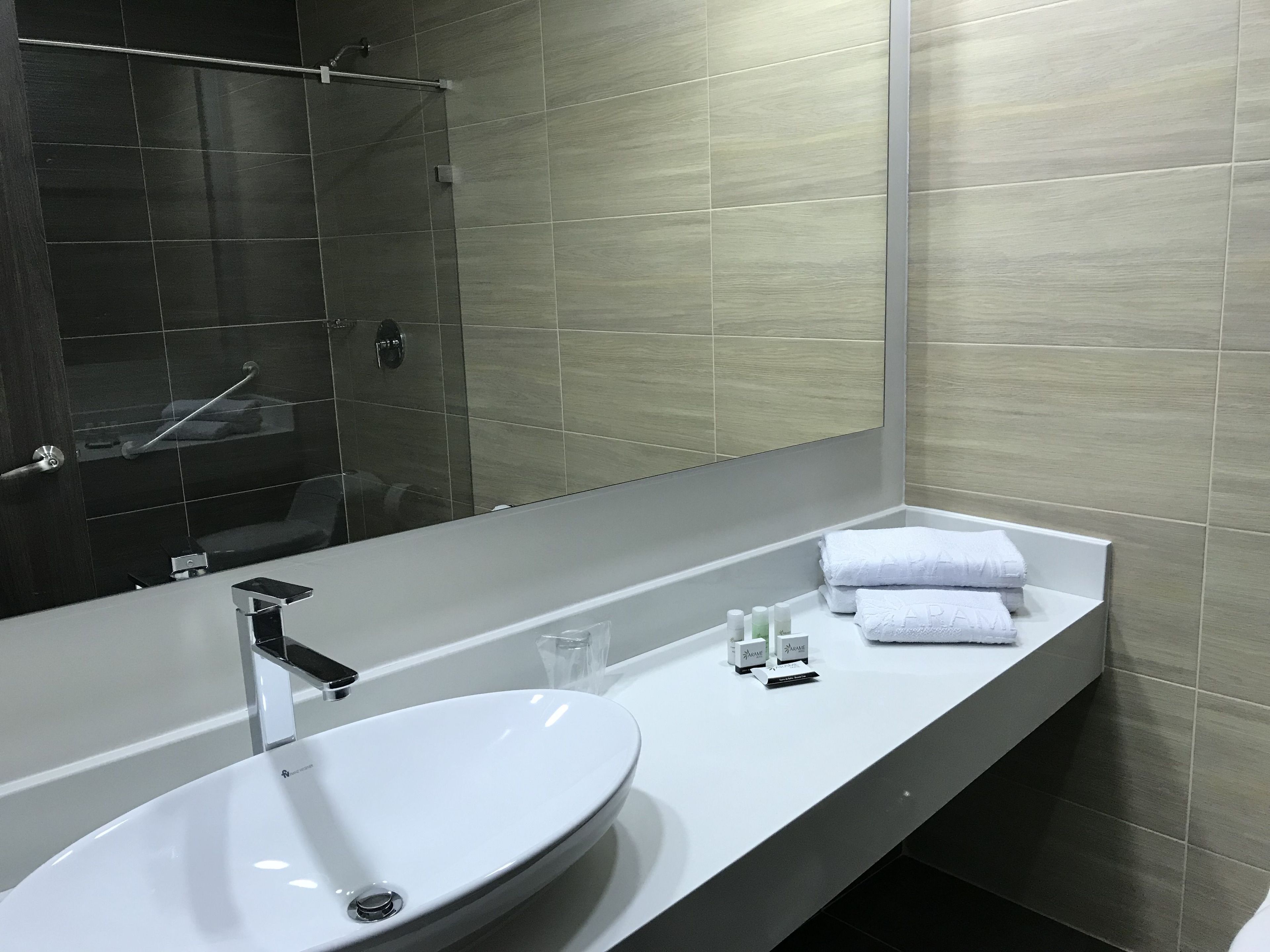 Uma casa de banho moderna com uma pia branca, um espelho grande e uma área de duche.