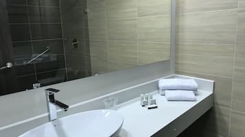 Uma casa de banho moderna com uma pia branca, um espelho grande e uma área de duche.