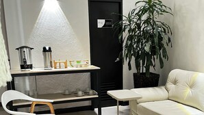 Una sala de estar moderna con una mesa de centro redonda de madera, sillas blancas, un sofá y una planta en maceta.