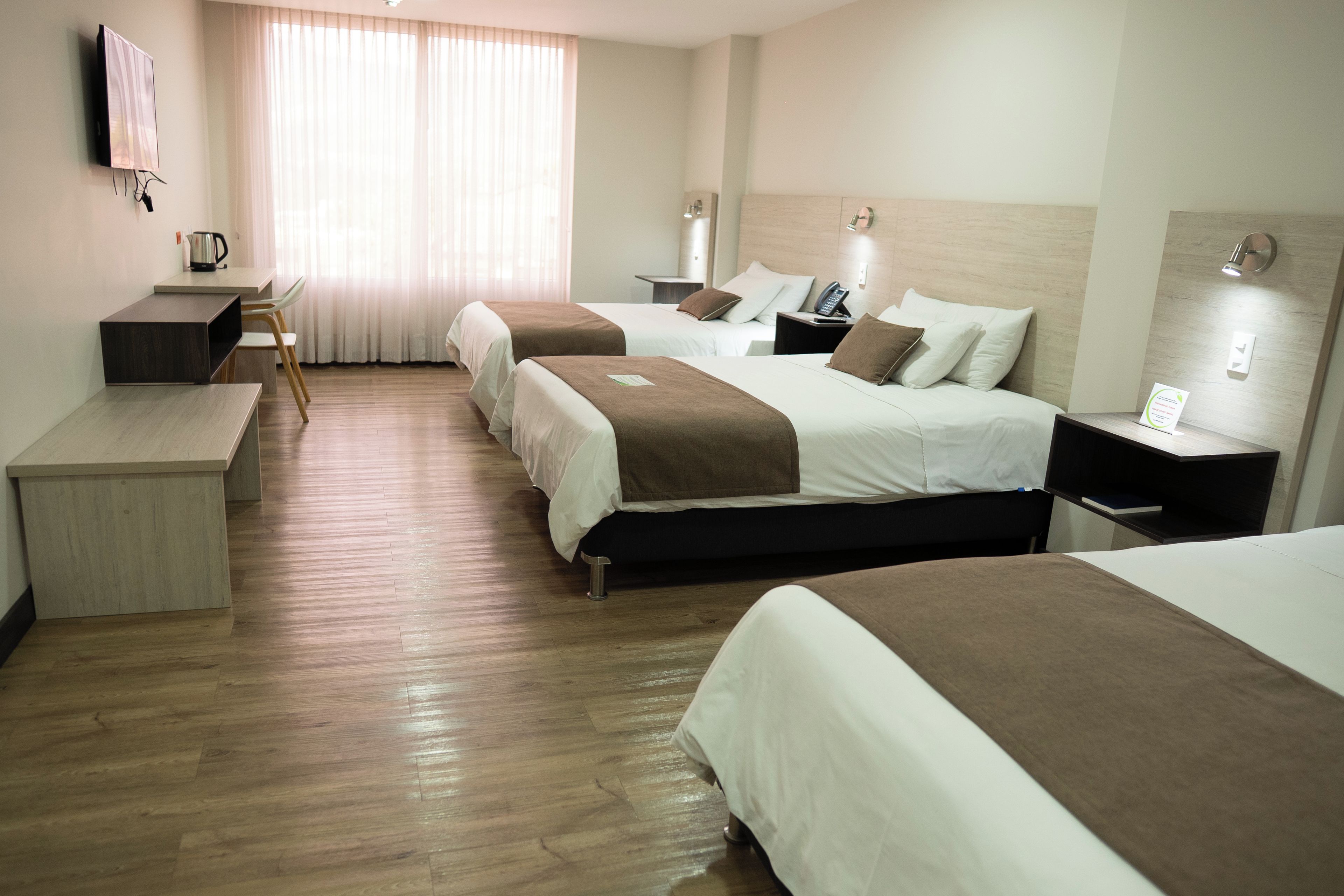 Een hotelkamer met twee bedden, een bureau, een stoel en een televisie.