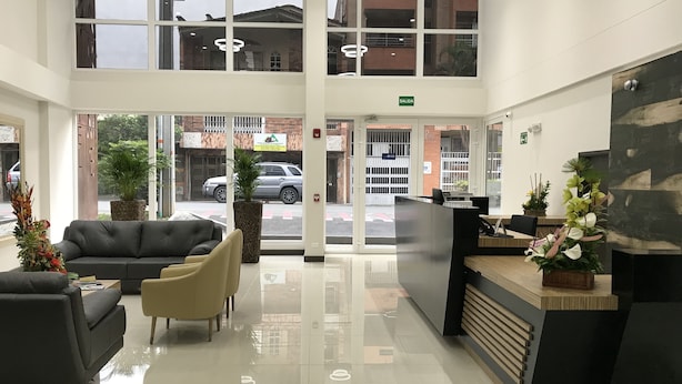 Un área de recepción moderna con entrada por puerta de cristal, mostrador de recepción y zona de estar.