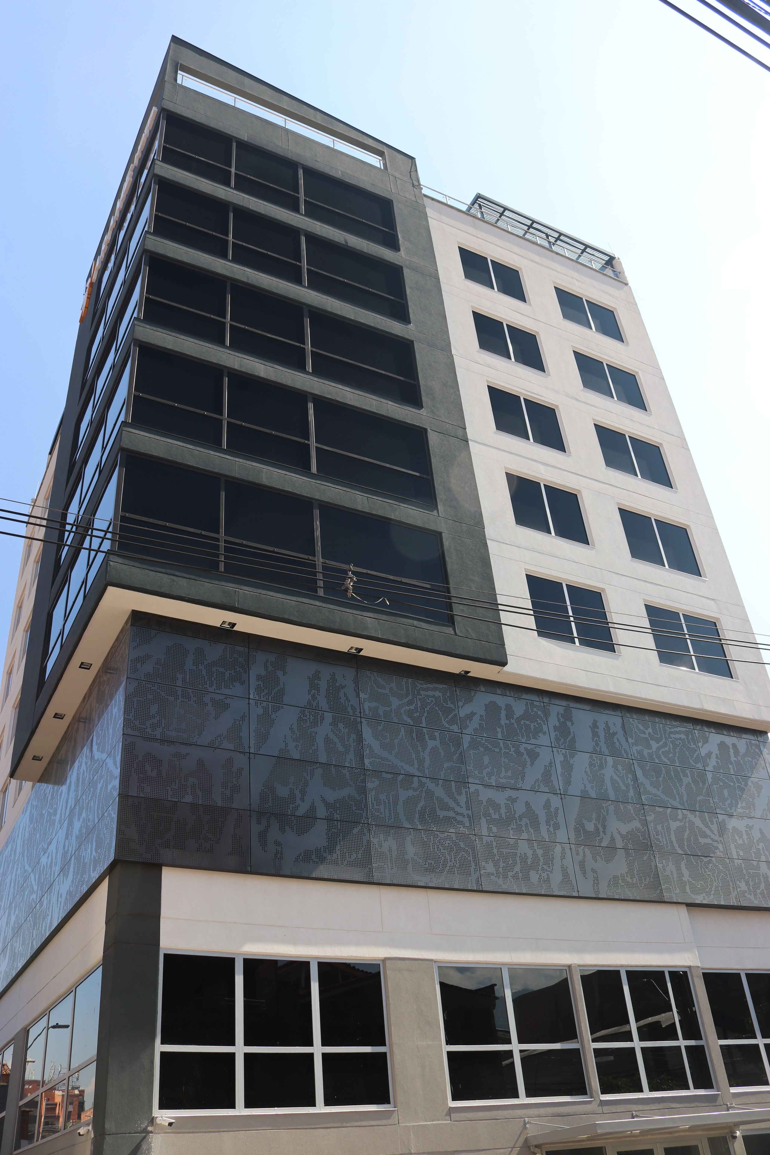 Un edificio de varios pisos con un diseño arquitectónico moderno, que destaca por sus amplios ventanales y una combinación de materiales de vidrio y hormigón.