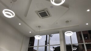 Un interior moderno con varias luces en el techo, ventanas amplias y un equipo de aire acondicionado visible.