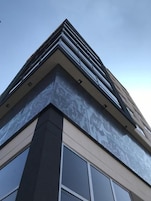 Un edificio moderno con un diseño de esquina llamativo, ventanas amplias y fachada con motivos decorativos.