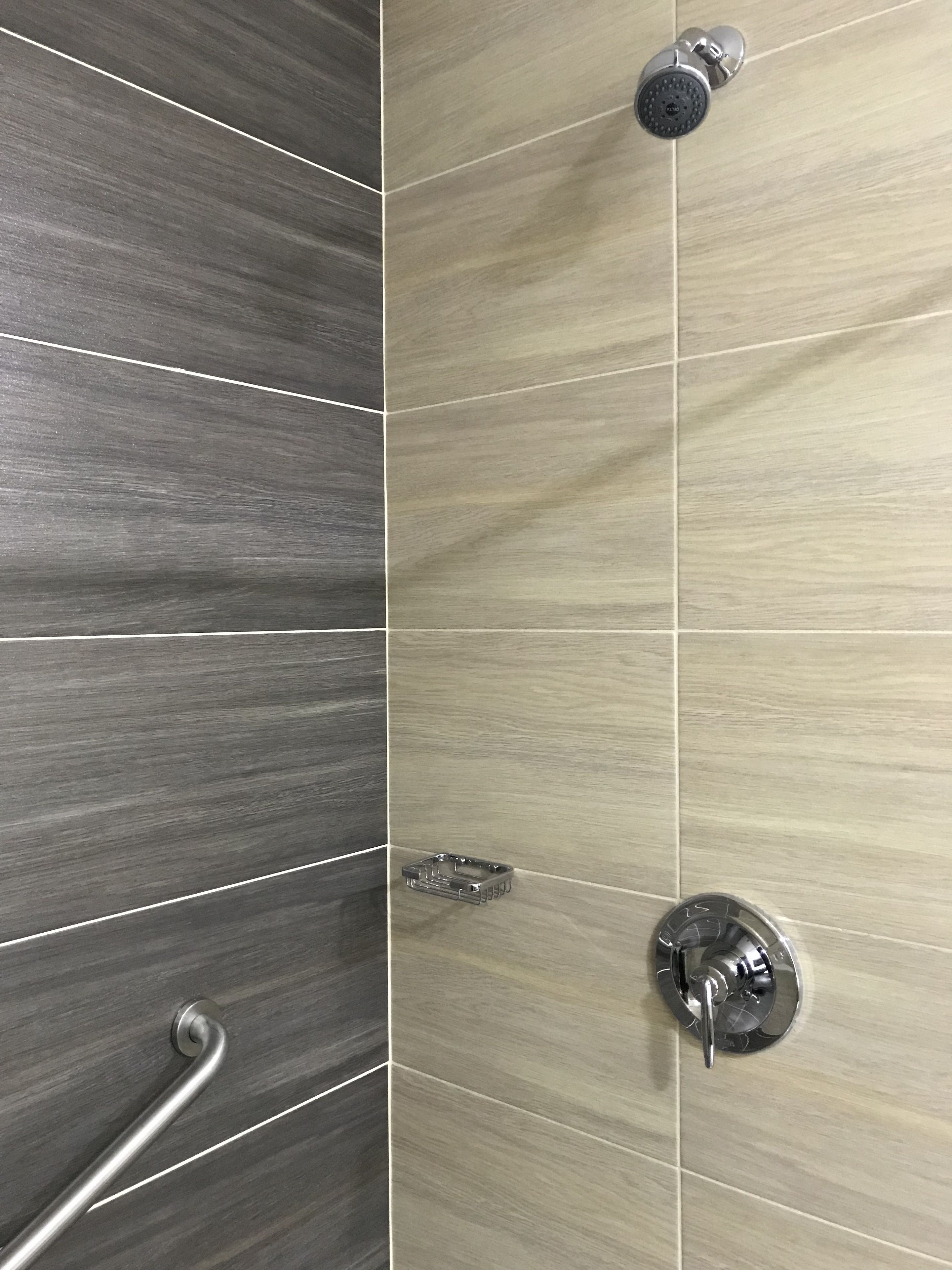 Ein Badezimmer mit Duschbereich, ausgestattet mit einer Regendusche und einer Handbrause.
