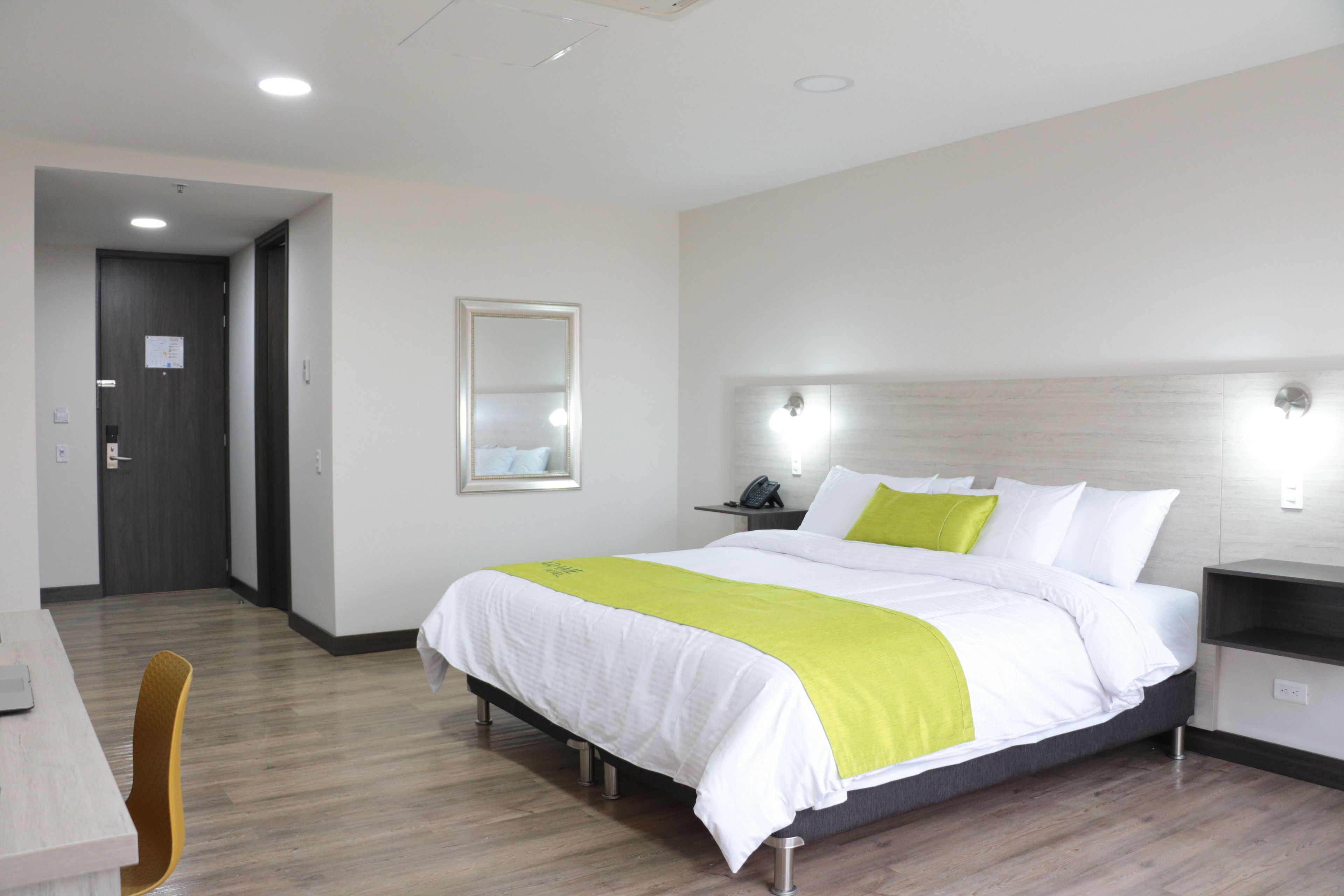 A hotel room with a bed, bedside tables, a chair, and a desk.