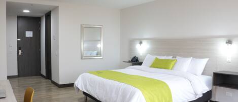 A hotel room with a bed, bedside tables, a chair, and a desk.