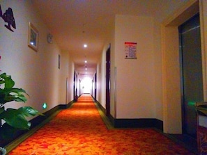 A long, narrow hallway with a carpeted floor, doors on both sides, and a sign on the wall. - GreenTree Inn Suzhou Zhangjiagang Daxin Town Pingbei Road Express Hotel (Suzhou)