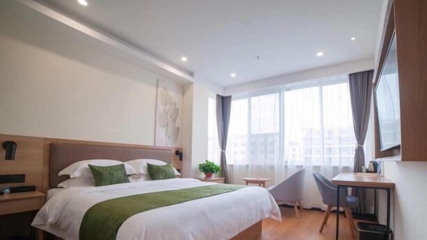 A modern hotel room with a large bed, a desk, and a chair. - GreenTree Inn Suzhou Zhangjiagang Daxin Town Pingbei Road Express Hotel (Suzhou)