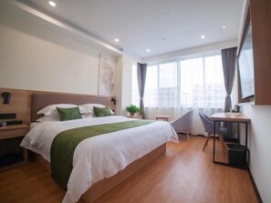 Ett modernt hotellrum med en stor säng, ett skrivbord och en stol.