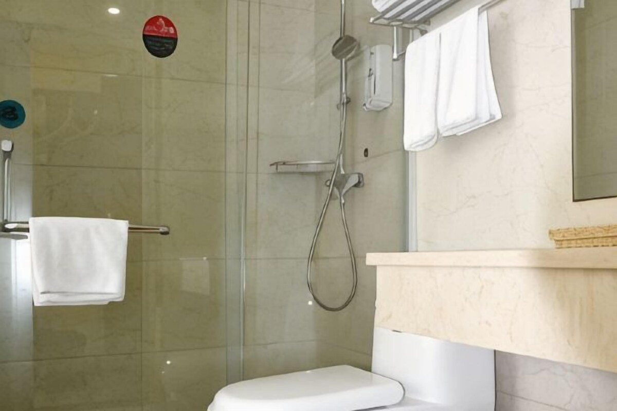 A modern bathroom with a glass-enclosed shower, a white toilet, and a beige countertop.