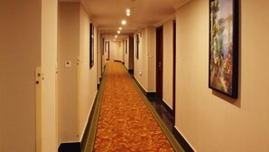 A long, carpeted hallway with doors on one side and a framed picture on the wall. - GreenTree Inn Prov. Suzhou Wuzhong Fengjin Rd Business Hotel (Suzhou)