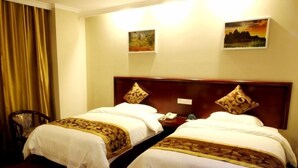 A hotel room with two beds, each with a wooden headboard and matching decorative pillows. There is a chair and a small table with a phone and a clock. - GreenTree Inn Prov. Suzhou Wuzhong Fengjin Rd Business Hotel (Suzhou)