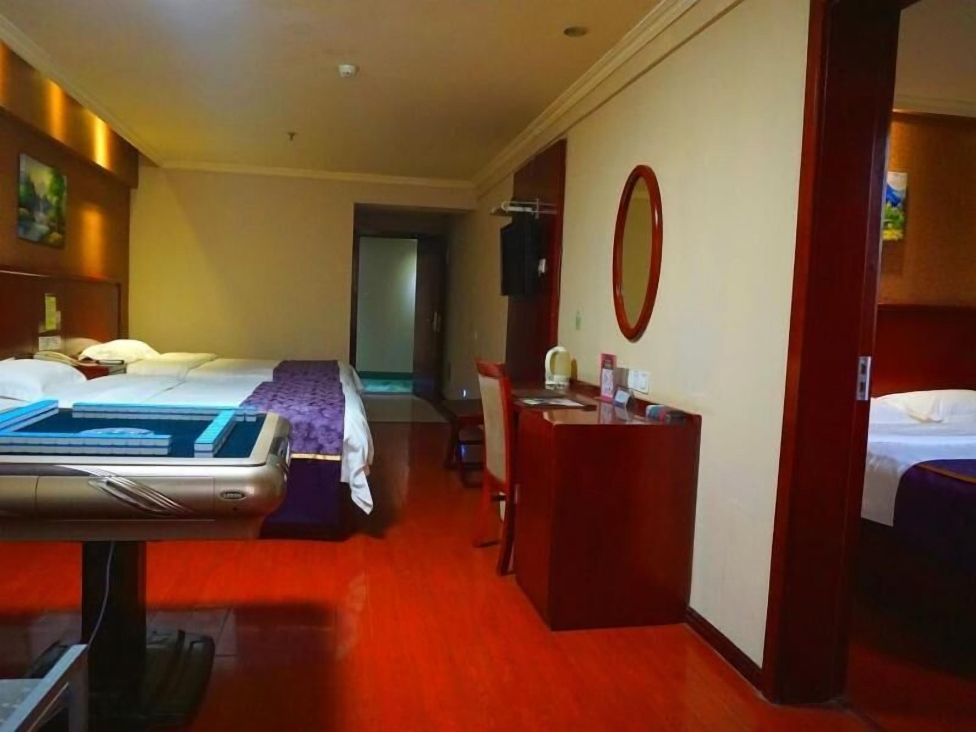 A hotel room with a bed, a desk, and a small seating area.