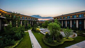 Un ensemble immobilier moderne composé de plusieurs bâtiments reliés entre eux, d’une allée centrale et de jardins aménagés.