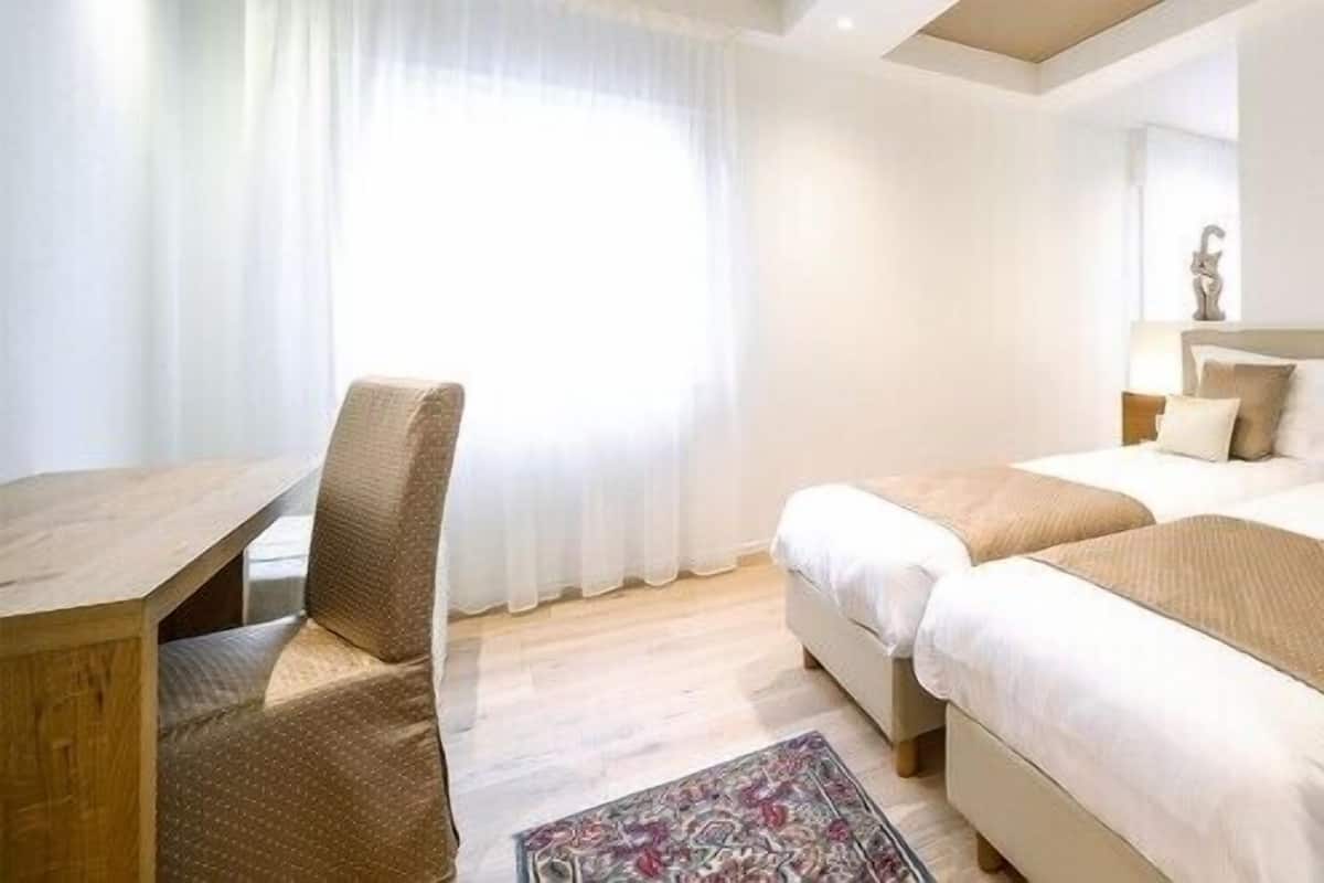 Une chambre d’hôtel avec deux lits, un bureau et une chaise.