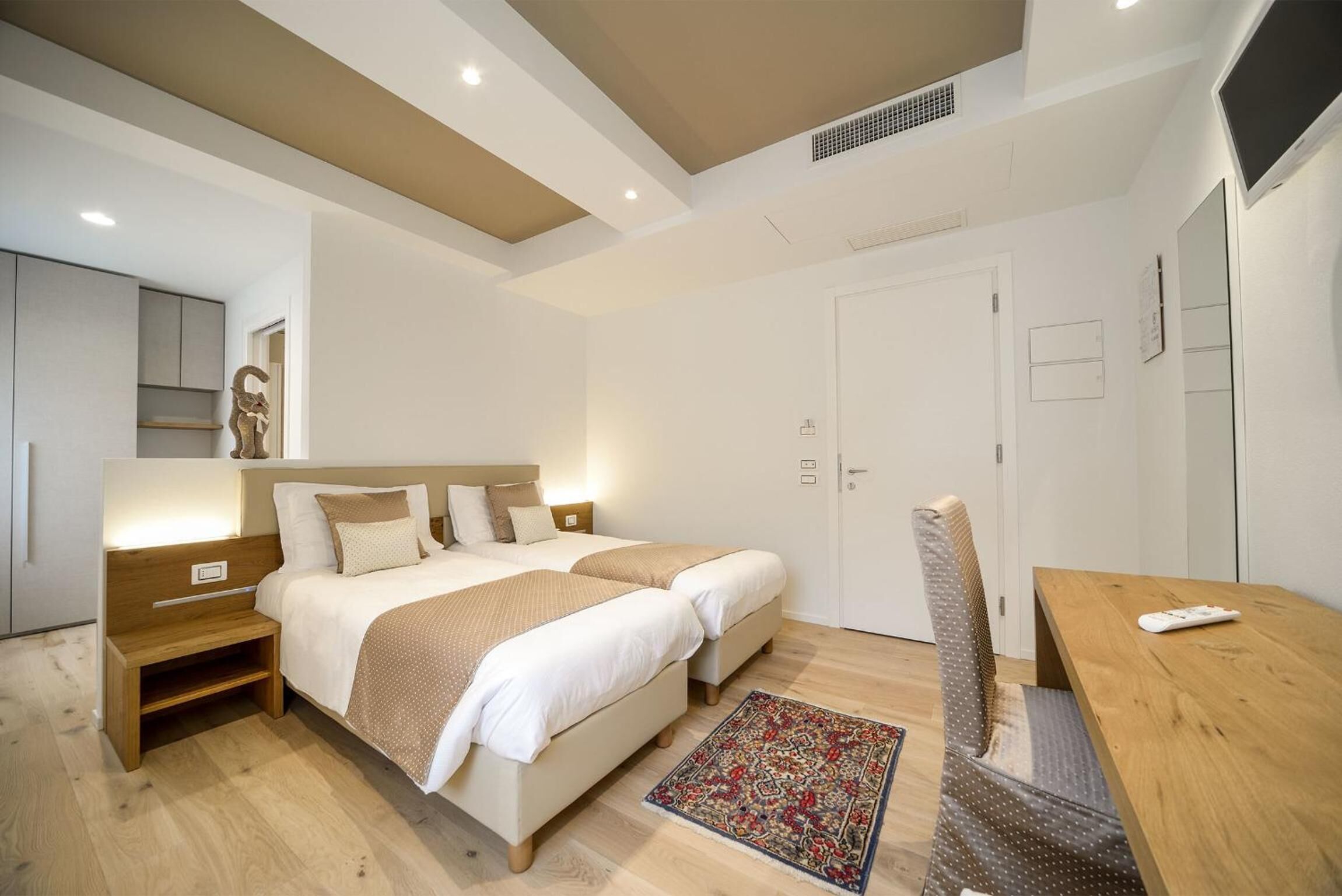 Une chambre moderne avec deux lits, une table de chevet en bois, un bureau et une chaise.