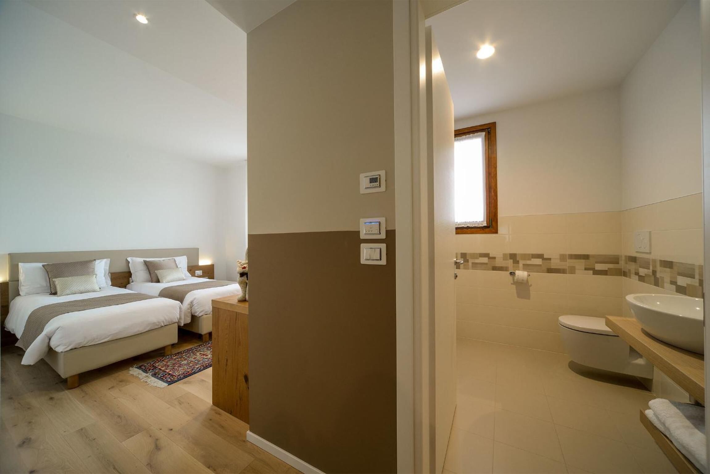 Ein Schlafzimmer mit zwei Betten, ein Badezimmer mit Toilette und Waschbecken sowie einer Dusche.