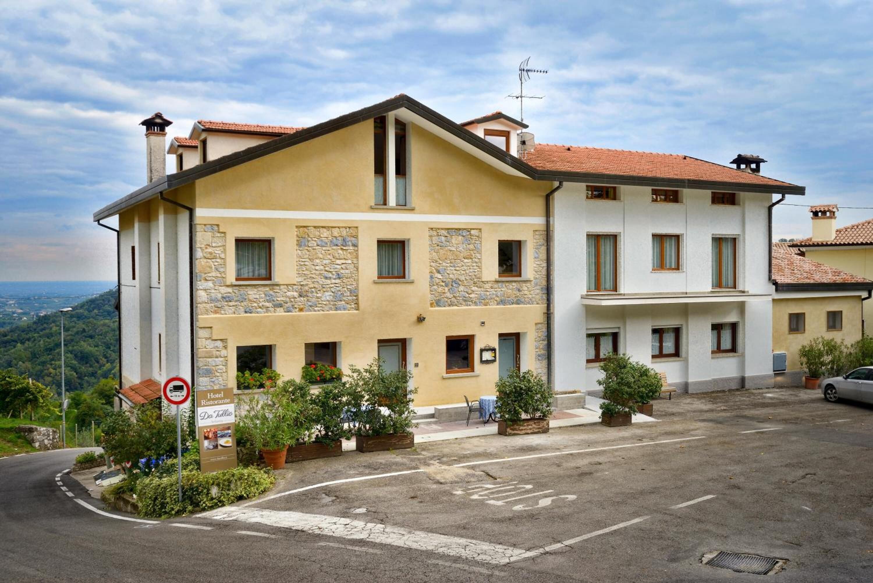 A two-story hotel with stone facade and a red-tiled roof.