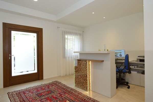 A modern office space with a desk, computer, and chair. There is a door with a glass panel and a window with curtains. - Ristorante Hotel da Tullio (Tarzo)