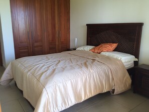 A bedroom with a bed, wooden wardrobe, and a nightstand. - Villa Jacaranda Sosua (Sosúa)