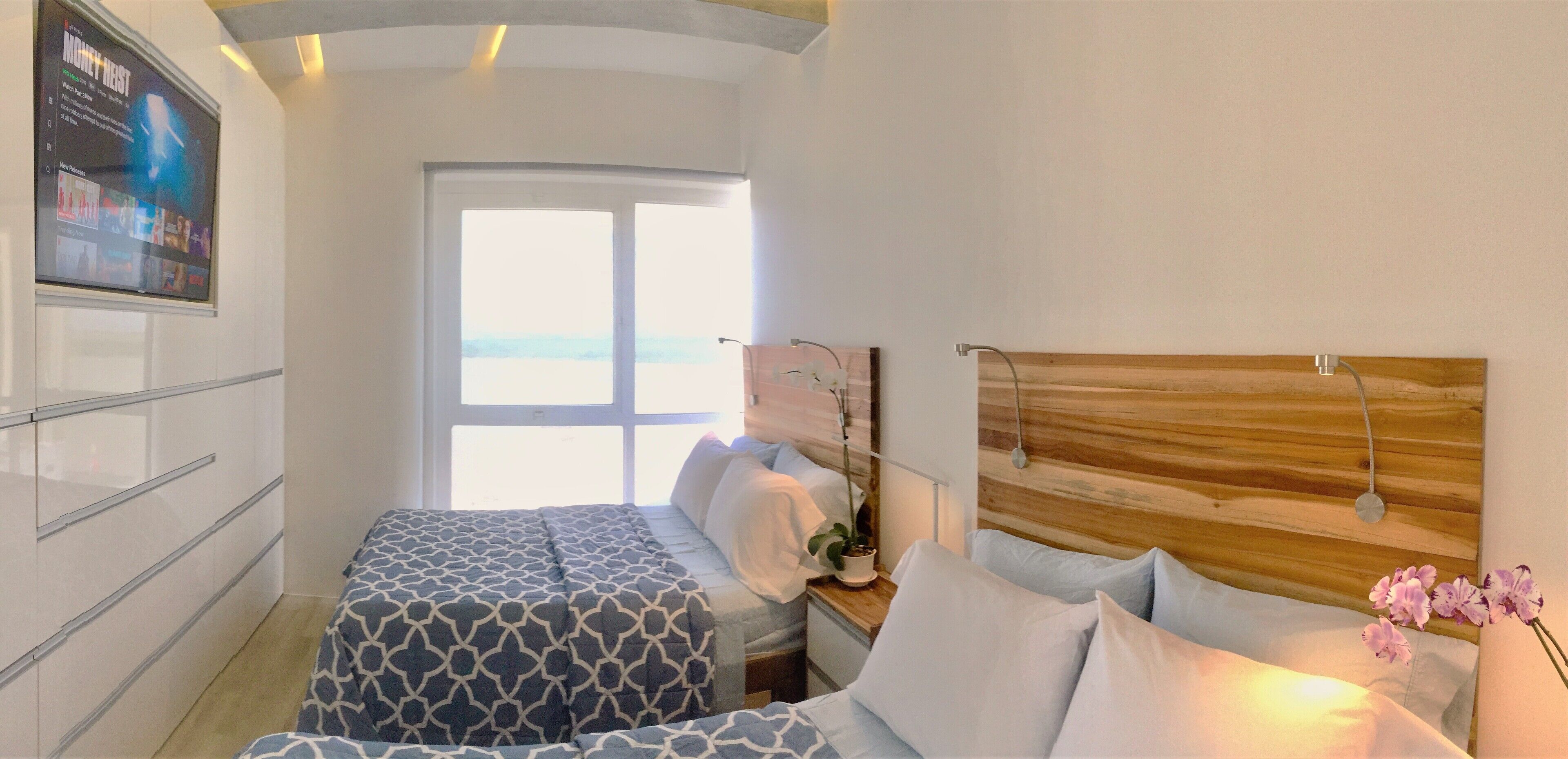 A bedroom with a bed, bedside table, and a window with a view.