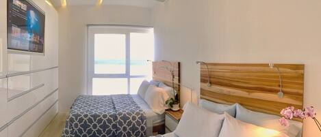 A bedroom with a bed, bedside table, and a window with a view.