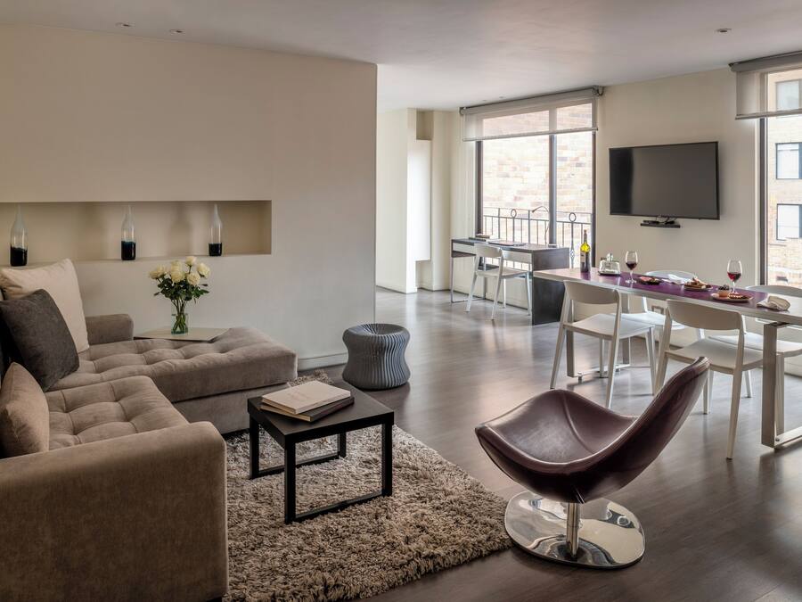 Una sala de estar moderna con un sofá, una mesa de centro y un comedor con una mesa y sillas.