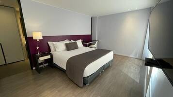 Une chambre d’hôtel moderne avec un grand lit, une table de chevet avec une lampe et un bureau avec une chaise.