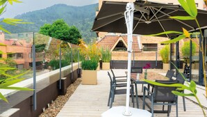A rooftop terrace with a table and chairs, a pergola, and potted plants. - Central Apartamentos Bogota (Bogotá)