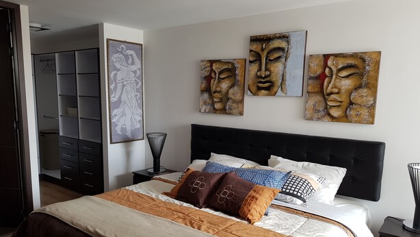 Ein Schlafzimmer mit einem großen Bett, einem Kleiderschrank und drei an der Wand befestigten Bildern.
