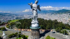 Eine große Statue eines Engels mit ausgebreiteten Flügeln, umgeben von einem kreisförmigen Platz mit einer Straße und Grünflächen.
