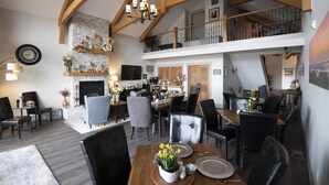 A spacious dining area with high ceilings and exposed beams, a fireplace, and a second-floor balcony. - Bella Collina Bed & Breakfast (Amity)