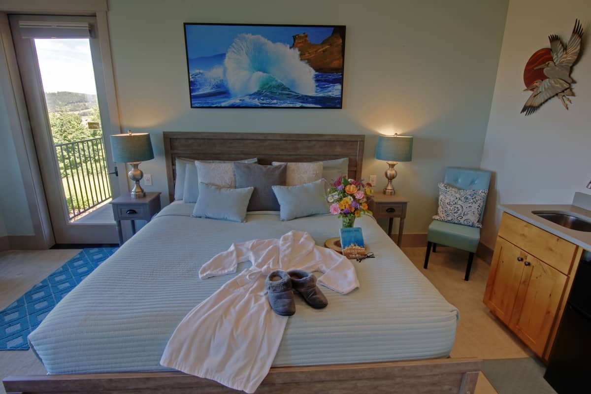 Een hotelkamer met een groot bed, uitzicht op zee, een balkon, een wastafel en een stoel.