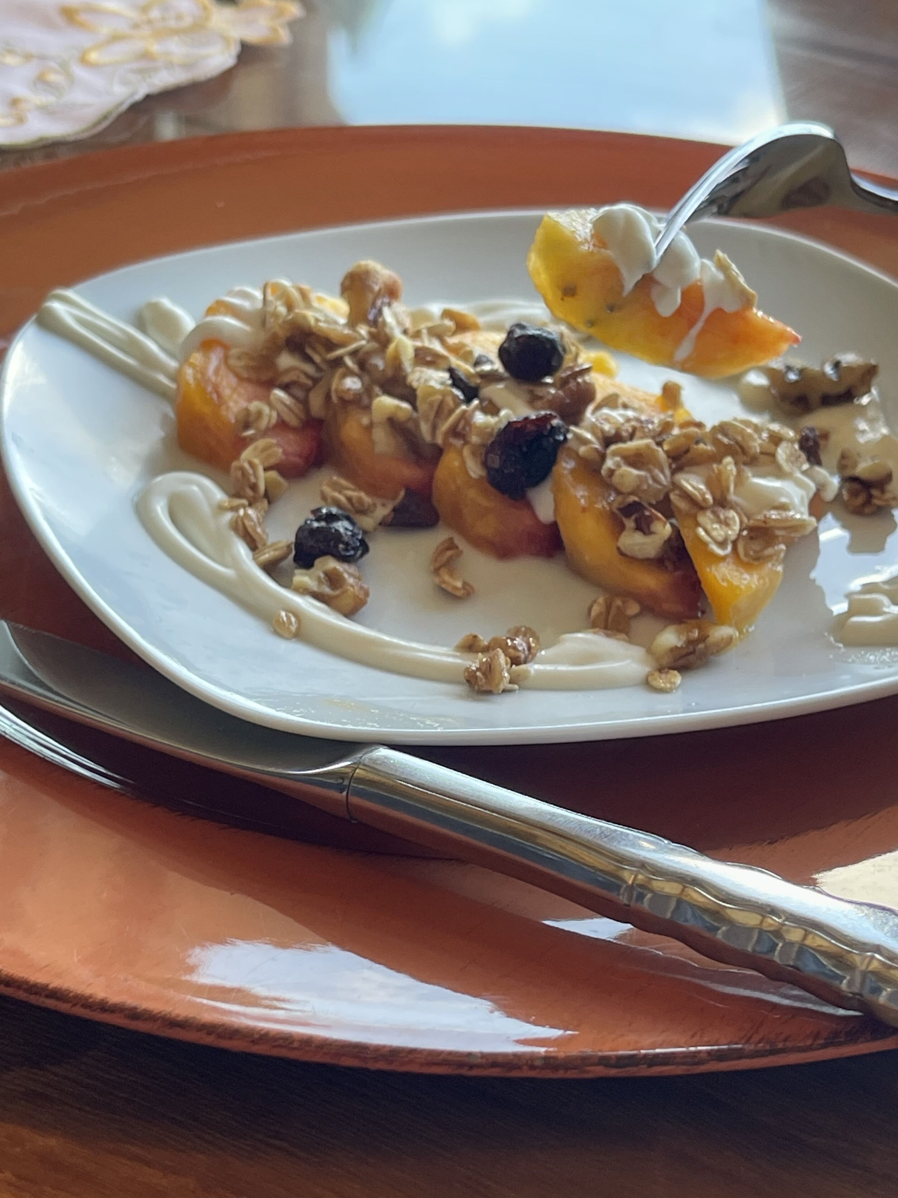 Un plato de comida con frutas, granola y yogur sobre un plato blanco.