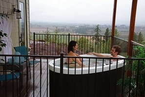 Un bain à remous sur un balcon offrant une vue sur un paysage rural.